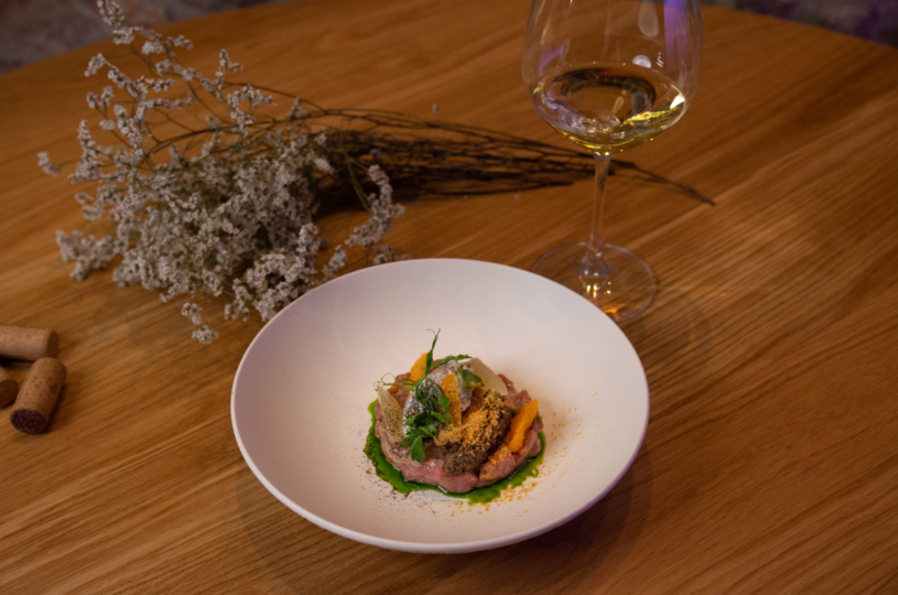 Lamb tartar with almond salad capers and almond cream with a glass of Tachtas P.G.I. Crete